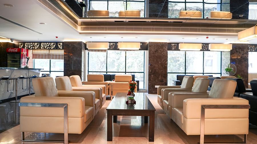  A modern and inviting seating area at BNGV Grandeur Hotel and Banquets, featuring light-coloured upholstered chairs and tables, with unique wall decor.