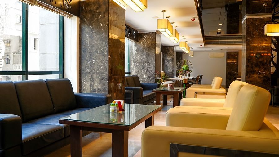 A wide shot of the elegant restaurant and seating area at BNGV Grandeur Hotel and Banquets, showcasing the arrangement of furniture and decorative elements.