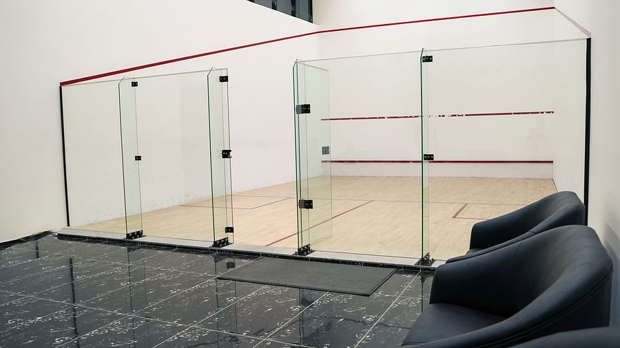 An indoor squash court with glass walls and a polished wooden floor at BNGV Grandeur Hotel and Banquets.