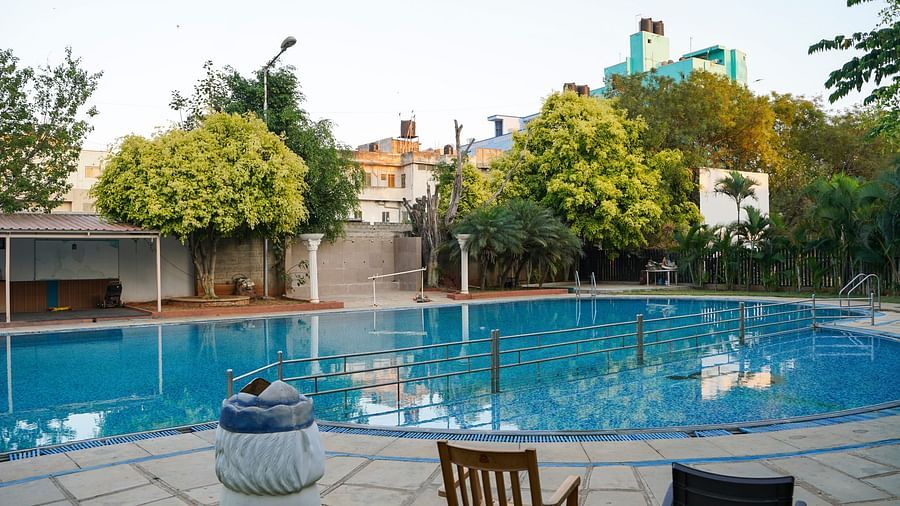 An outdoor swimming pool at BNGV Grandeur Hotel and Banquets, with clear blue water and surrounding greenery.