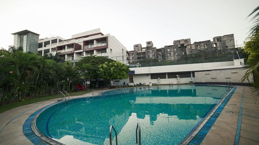 An outdoor swimming pool with blue water and surrounding buildings, part of BNGV Grandeur Hotel and Banquets.