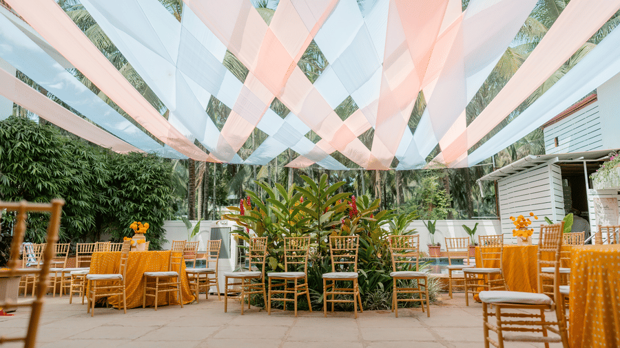 An outdoor seating layout featuring a fabric canopy, chairs, tropical foliage at Bougainvillea, Alibaug.