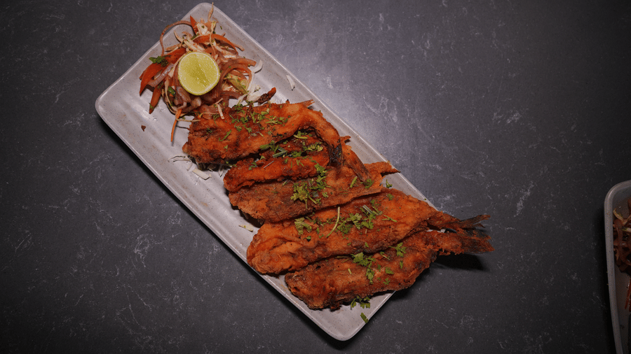 A rectangular platter holds pieces of fried fish, a lemon wedge, and a side salad at Bougainvillea, Alibaug.