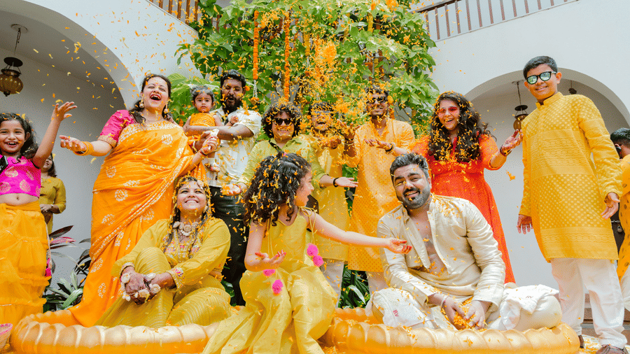 People celebrating a haldi ceremony with yellow clothing, flower petals, decorative tubs at Bougainvillea, Alibaug.