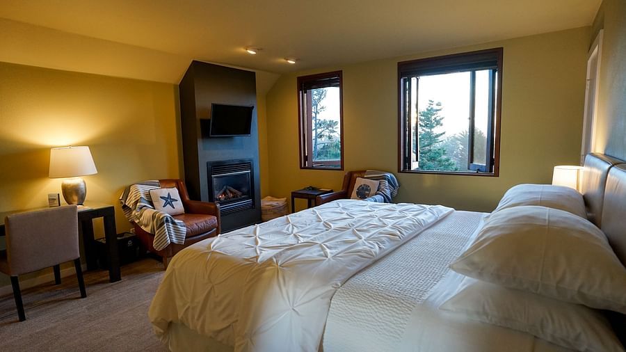 A hotel room featuring warm yellow lights, a bed, furniture and windows with scenic views - Brewery Gulch Inn & Spa