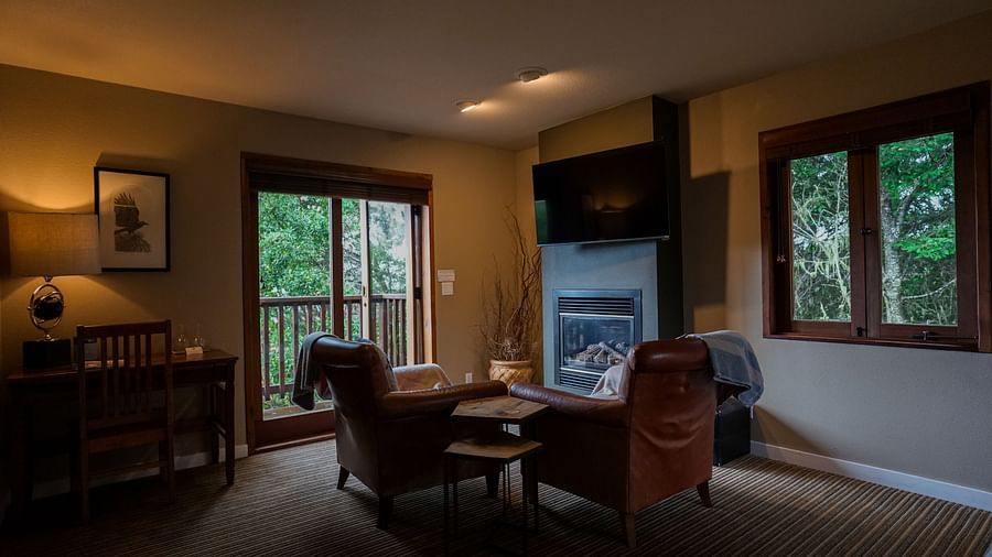 Stylish room featuring a comfortable armchair and a private balcony overlooking nature - Brewery Gulch Inn & Spa