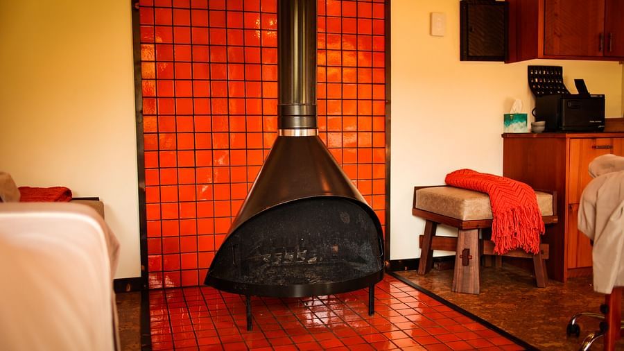 Massage Room with a red-tiled fireplace, white linens, and warm lighting - Brewery Gulch Inn & Spa