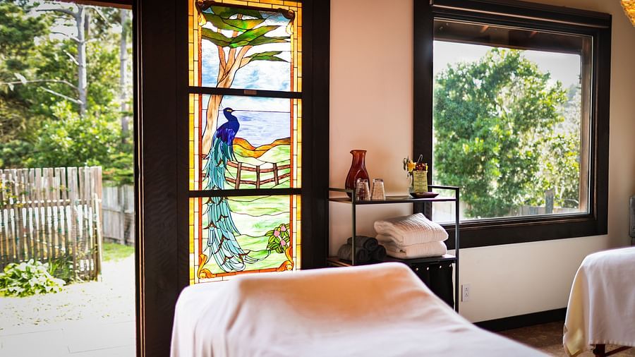 Massage Room with large windows, white linens, and a painted-glass window accent - Brewery Gulch Inn & Spa