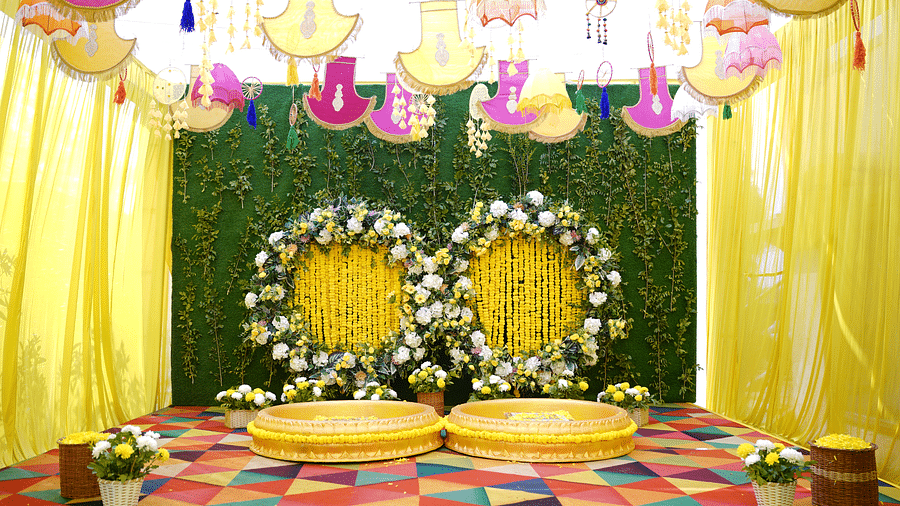 Brij Eternity, Vrindava |  A stage with floral backdrops, golden seating, and vibrant yellow drapery for wedding ceremonies.