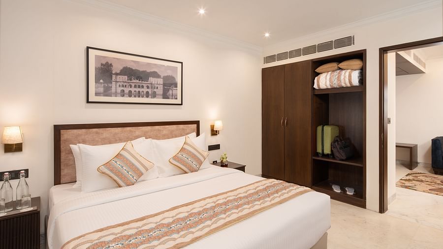 An image of a bedroom with bedside table, photo frame hanged on the wall, work desk with sofa chair, a flat TV screen, and a wardrobe - Brij Eternity, Vrindavan
