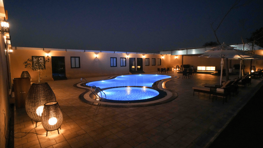 Evening courtyard at Brij Eternity Vrindavan featuring lit pool, ambient lanterns, guest seating and peaceful architectural layout