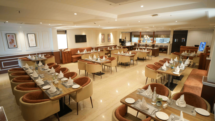 Tulsi Ark, multi-cuisine restaurant at Bel Eternity Hotel, featuring neatly arranged dining tables, cushioned chairs, and warm lighting.