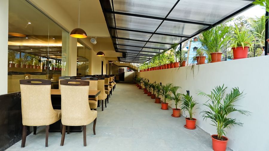 Back view of a dining area with tables and chairs and pots of plants on the side at Calux Grand Baga.