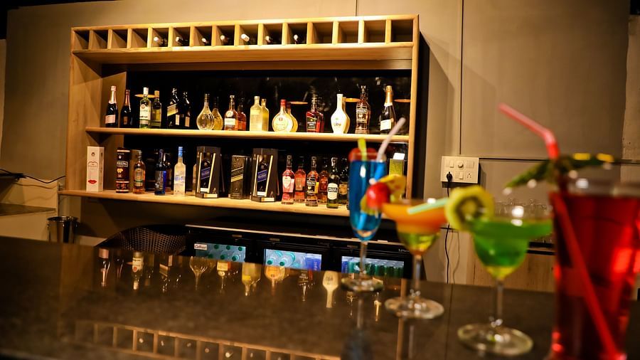 Image of a bar with drinks on the counter table and drinks placed in a shelf behind at Calux Grand Baga.