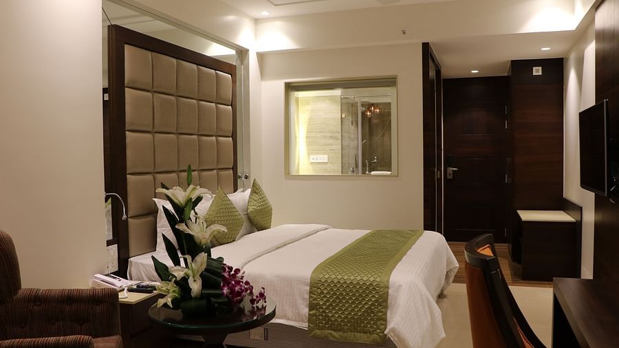 Side view of a room with a bed and a table with flowers beside it at Calux Grand Inn, Calangute.