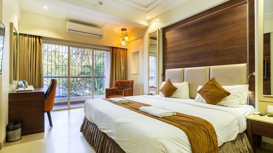 Image of a room with a bed and a table with a chair in the corner at Calux Grand Inn, Calangute.