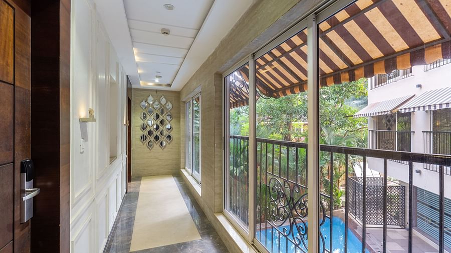 Image of a corridor with doors on one side and a view of the surrounding area on the other side at Calux Grand Inn, Calangute.