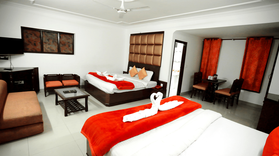 Room with twin beds and a seating area in the corner at Calux Hill Queen, Mussoorie.