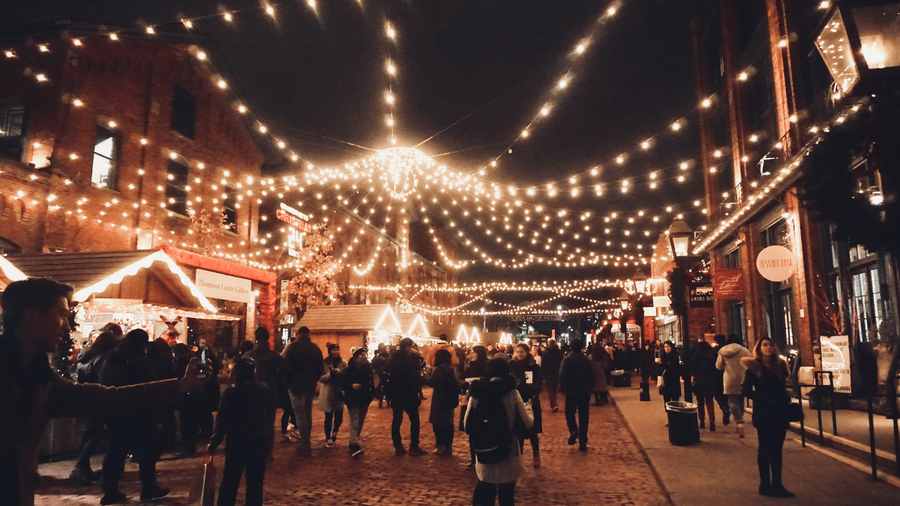 people walking on a road under a string of light at night