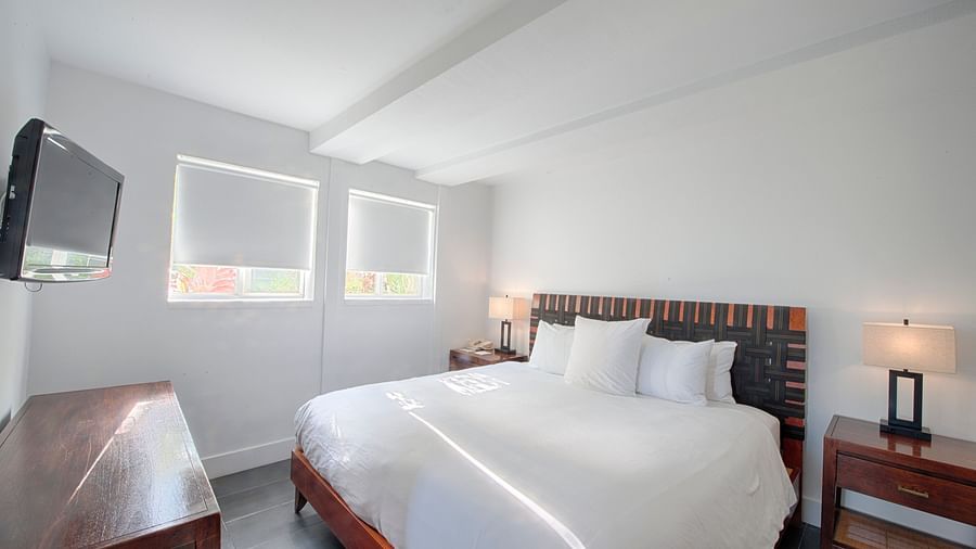 Bedroom at Casa Morada featuring a white bed, wooden furniture, and a wall-mounted TV.