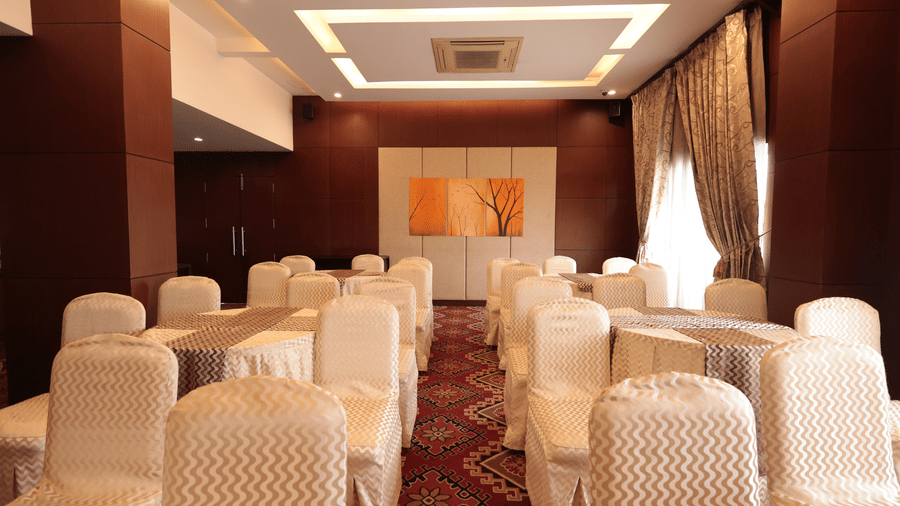 A small banquet hall with well-decorated chairs and curtains draped over the windows | Cenneys Gateway