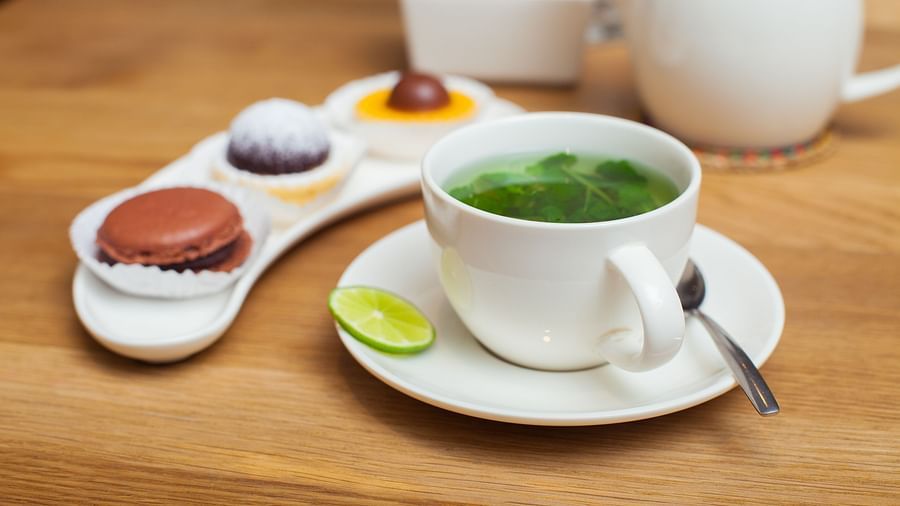 A white plate with a few small desserts and a cup of green tea on a wooden table | The Shop | Central Mansions, Phnom Penh