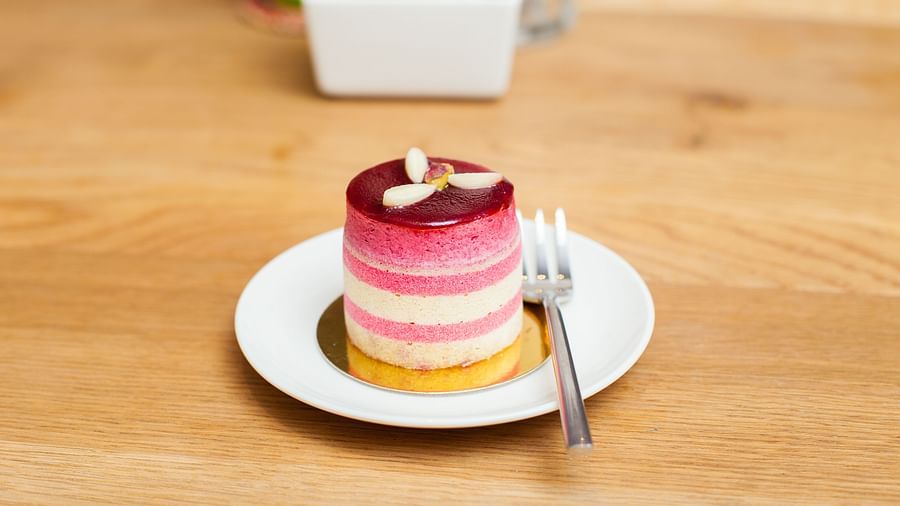 A small cake on a white plate with two forks on a wooden table | The Shop | Central Mansions, Phnom Penh