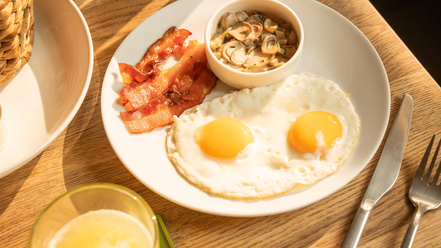 Breakfast plate featuring eggs, grilled tomatoes, bread, and a bowl of yoghurt at Central Mansions, Phnom Penh.