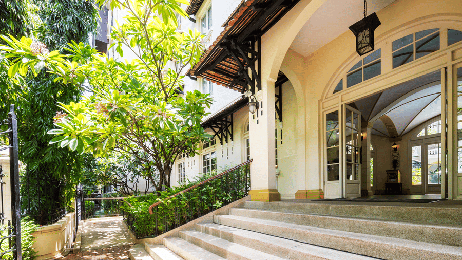 Covered exterior walkway with an arched entrance and landscaped surroundings at Central Mansions, Phnom Penh.