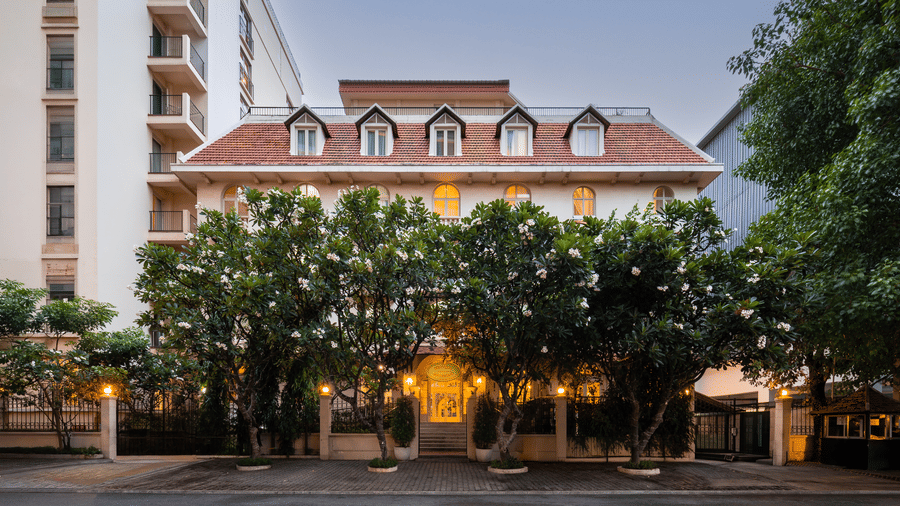 Exterior view of the Central Mansions, Phnom Penh, with landscaped surroundings and a red tiled roof.