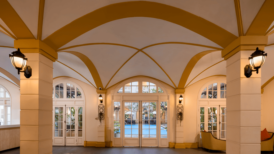 Grand entrance hall with arched ceilings, wall lighting, and glass doors at Central Mansions, Phnom Penh.