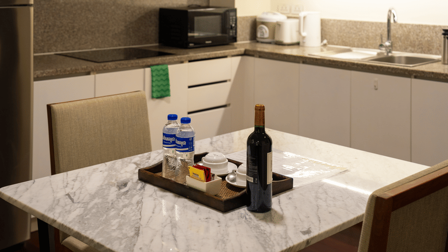 Kitchen and dining area with a marble table, chairs, microwave, and kitchenette.