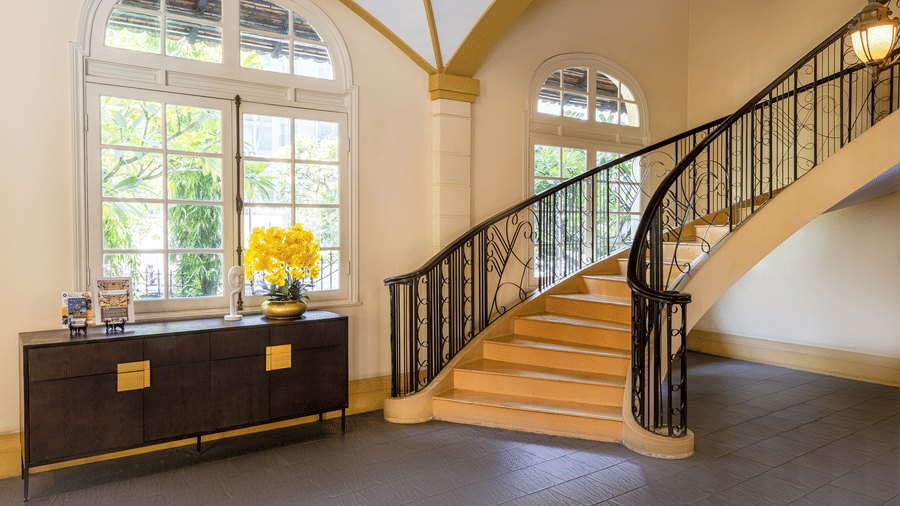 Lobby area featuring a staircase, arched windows, and elegant furnishings at Central Mansions, Phnom Penh.