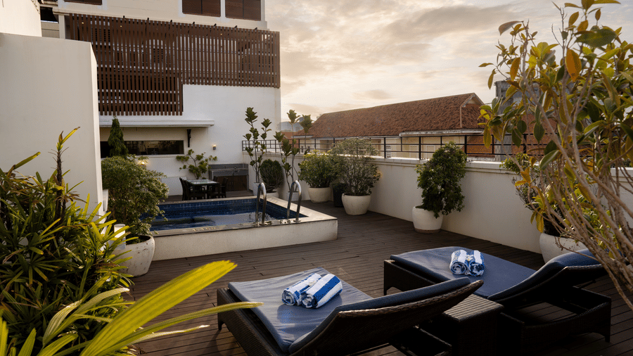 Outdoor terrace with lounge seating, sun loungers, and potted plants at Central Mansions, Phnom Penh.