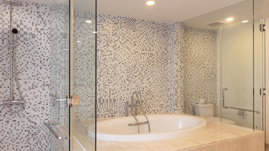 Penthouse bathroom at Central Mansions, Phnom Penh featuring a bathtub, glass shower enclosure, and mosaic tiled walls.