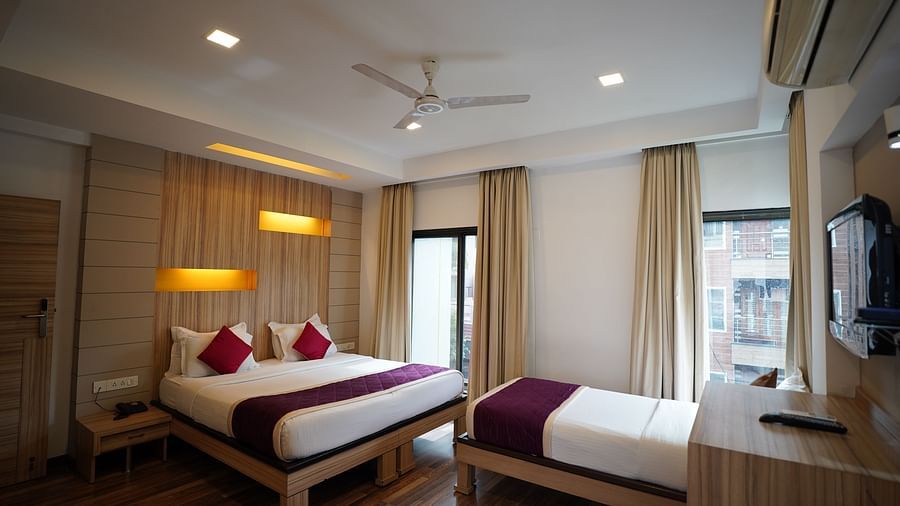 an image of executive deluxe room with a bed and a cot near the window at  City Centre Residency, Bangalore