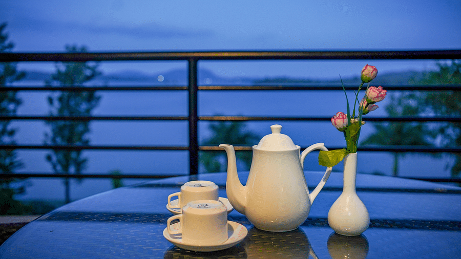 Image of a teapot and two cups placed on a table alongside a vase of flowers at Coorg Jungle Camp Backwater Resort, Kushalnagar.