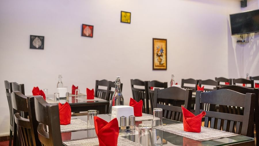 Image of a dining space with tables and chairs and frames on the wall at Coorg Jungle Camp Backwater Resort, Kushalnagar.
