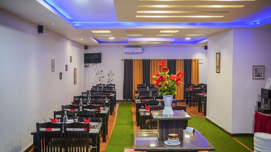 Image of a dining space with tables and chairs a lights on the ceiling at Coorg Jungle Camp Backwater Resort, Kushalnagar.