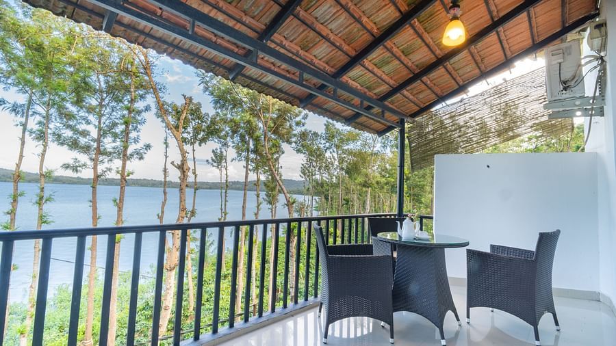Image of a seating area with chairs and a table with a view of the nature around it at Coorg Jungle Camp Backwater Resort, Kushalnagar.