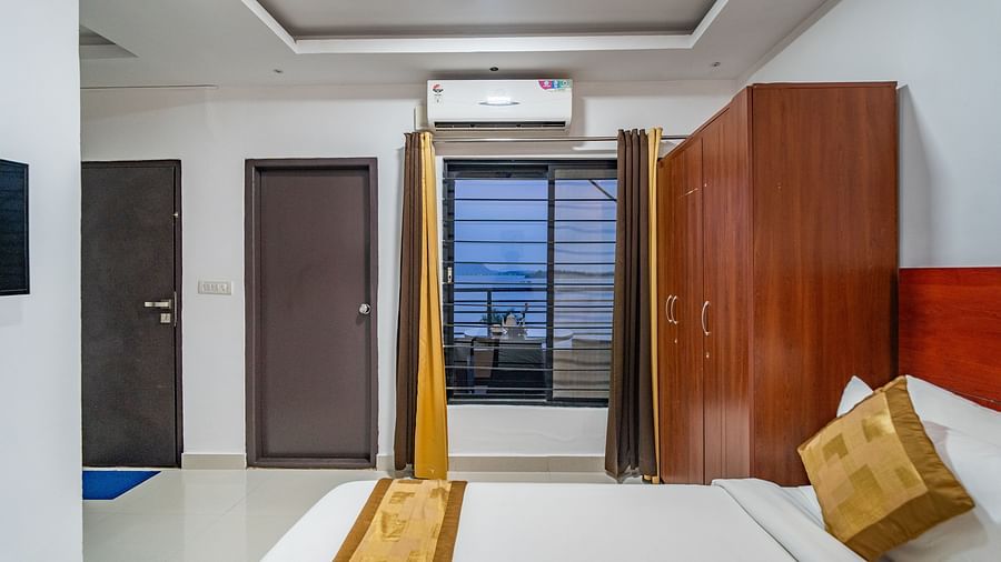 Side view of a room with bed and a window on the side with the curtains  open at Coorg Jungle Camp Backwater Resort, Kushalnagar.