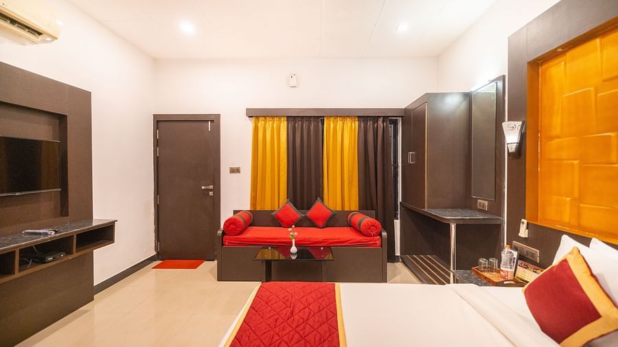 Side view of a room with a bed with a sofa on the side and a window behind it at Coorg Jungle Camp Backwater Resort, Kushalnagar.
