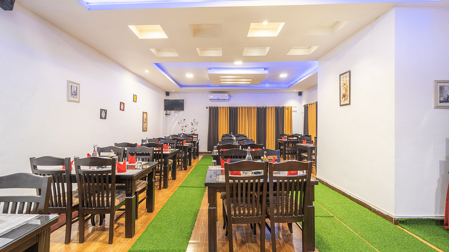 Image of a dining space with seating area and green carpets on the floor at Coorg Jungle Camp Backwater Resort, Kushalnagar.