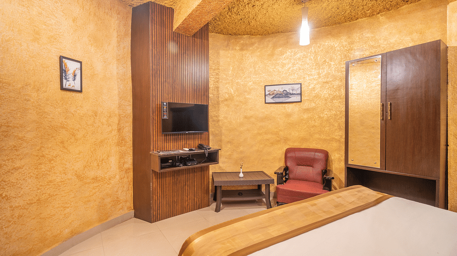 Side view of a room with a television and a chair on the side at Coorg Jungle Camp Backwater Resort, Kushalnagar.