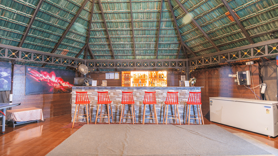 Image of a bar with chairs and drinks behind the counter table at Coorg Jungle Camp Backwater Resort, Kushalnagar.