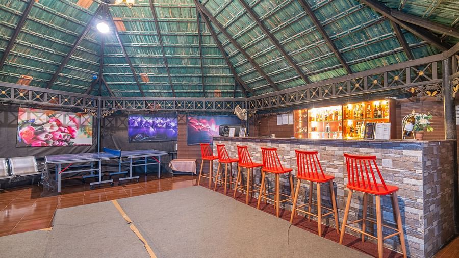 Image of a bar with high chairs placed in front of the bar at Coorg Jungle Camp Backwater Resort, Kushalnagar.