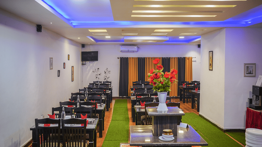 A dining space with tables and chairs and lights on the ceiling at Coorg Jungle Camp Backwater Resort, Kushalnagar.