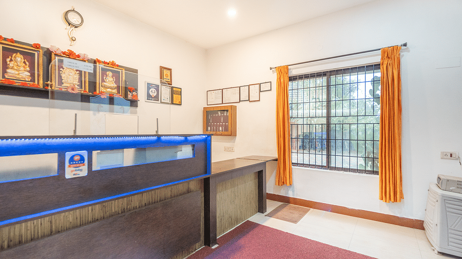 Image of a reception area with a table with a window with open curtians on the side at Coorg Jungle Camp.