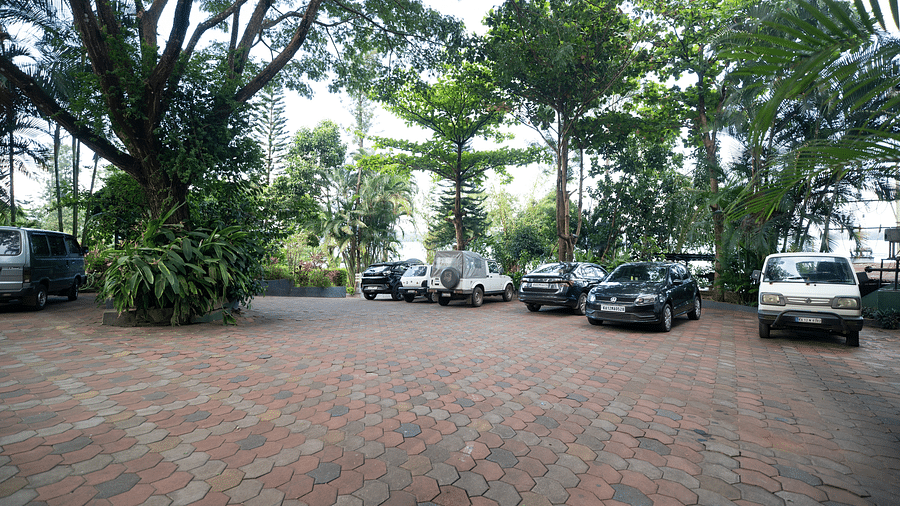 Image of an open area with cars parked and trees around it at Coorg Jungle Camp.