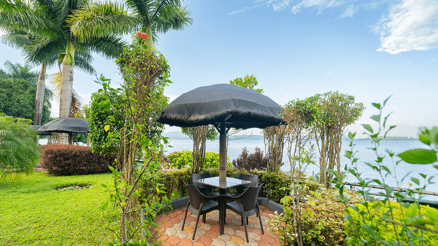 Image of seating area with tress around it and a waterbody in the background at Coorg Jungle Camp.